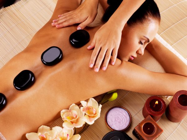 Adult woman having hot stone massage in spa salon. Beauty treatment concept.